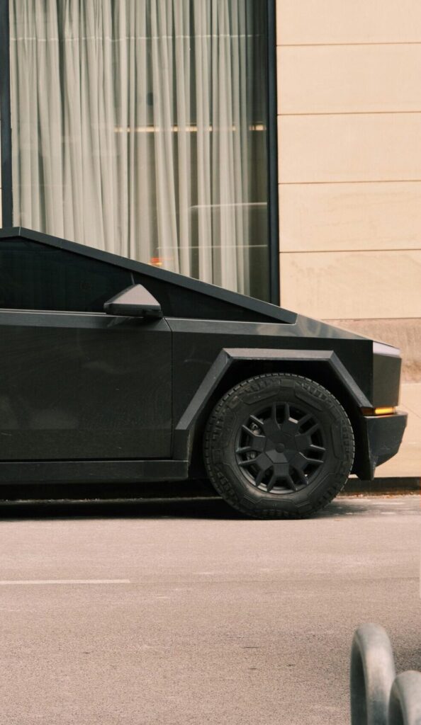 Sleek and futuristic black car parked on a city street near modern building.