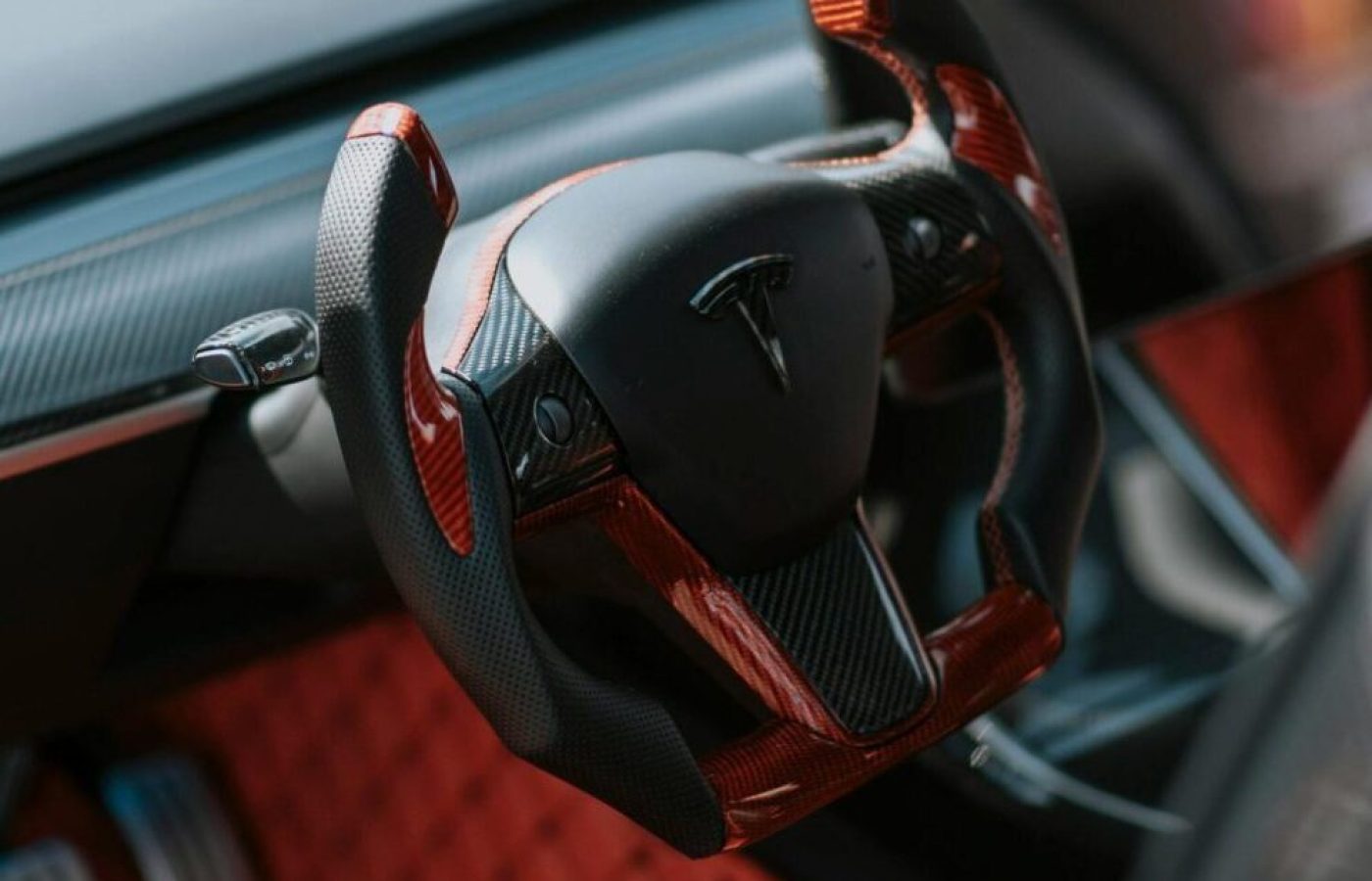 Close-up of a luxury electric car's red and black interior featuring a sleek steering wheel.