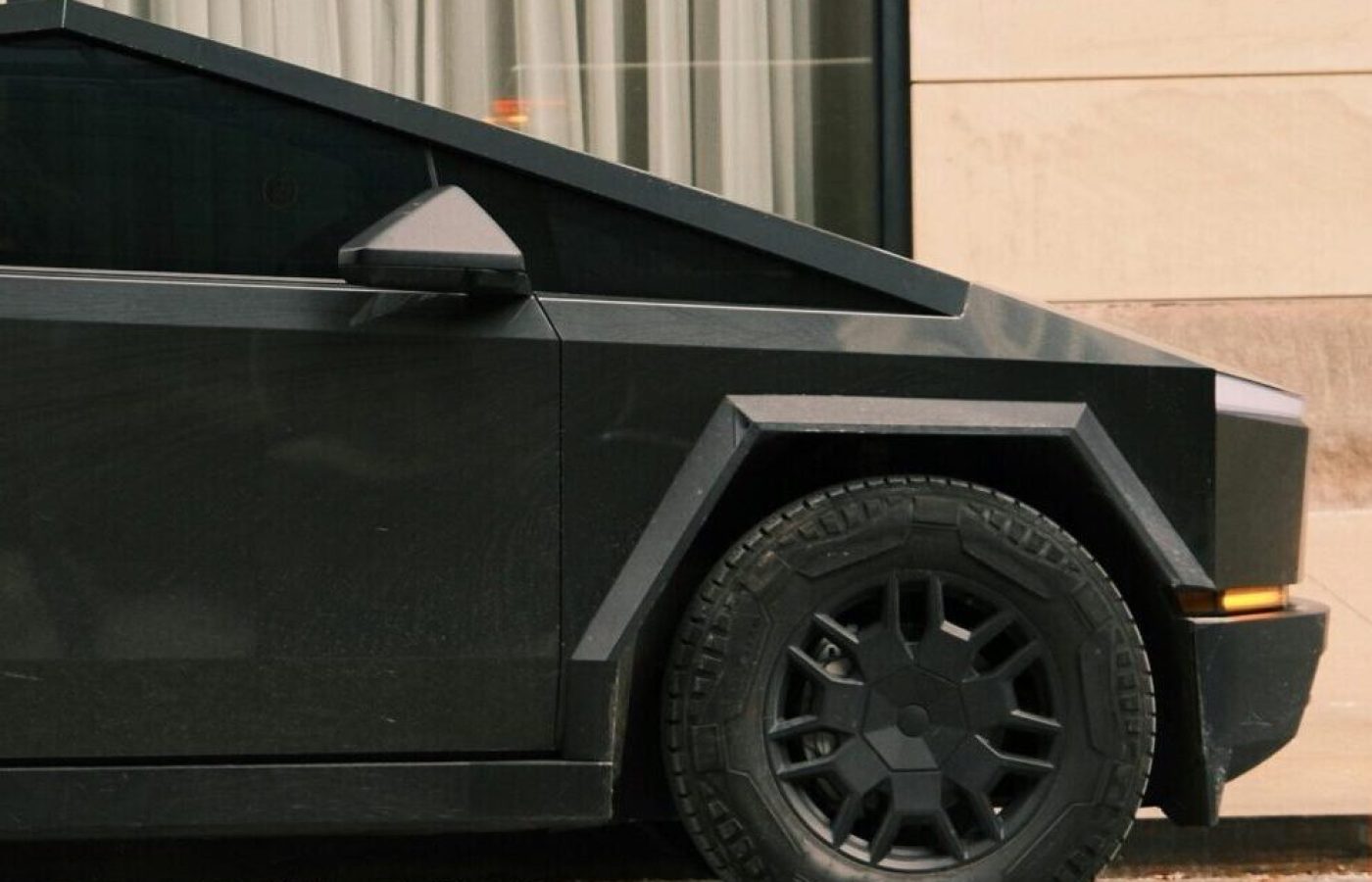Sleek and futuristic black car parked on a city street near modern building.